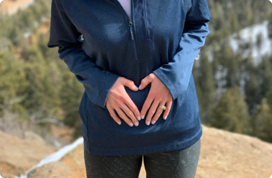 Femme debout avec les mains sur le ventre, représentant la possibilité de rencontres intimes significatives et épanouissantes après la chirurgie de stomie.