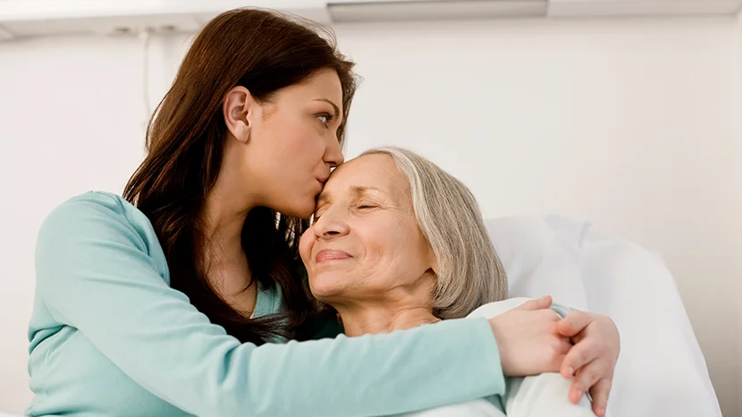 Frau gibt Frau Kuss auf die Stirn.